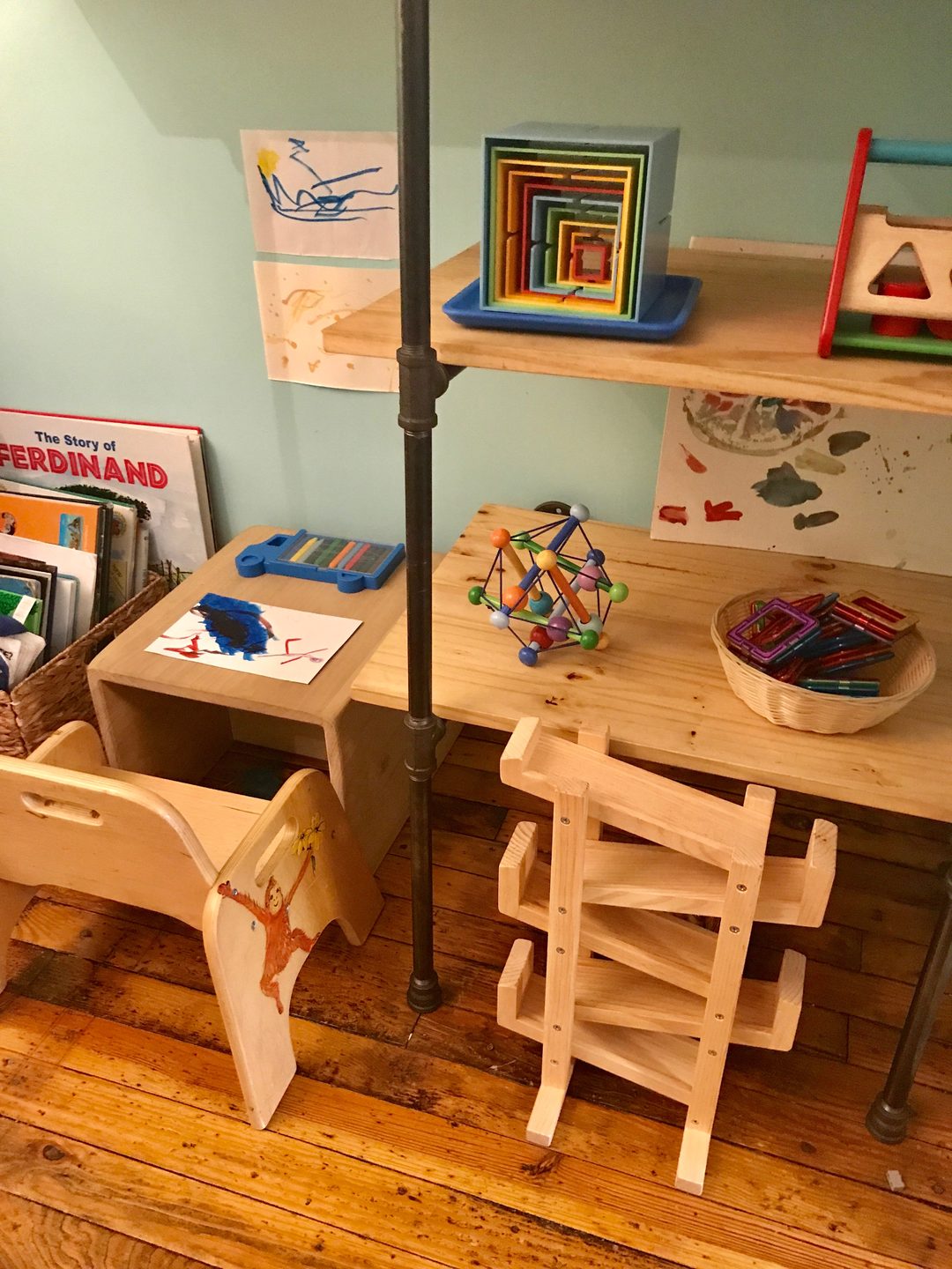 A toddler-height table and chair beside a low shelf of wooden puzzles and baskets.